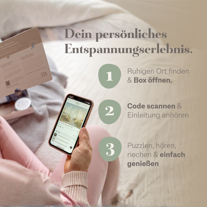 Person sitzt auf einem Bett, hält Smartphone mit geöffneter App, im Hintergrund eine geöffnete Puzzle-Schachtel und Puzzle-Teile sichtbar.